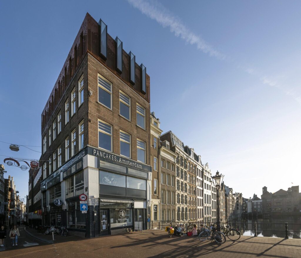 Straatbeeld van de Prins Hendrikkade in Amsterdam met het hoekpand waarin PANCAKES Amsterdam is gevestigd.